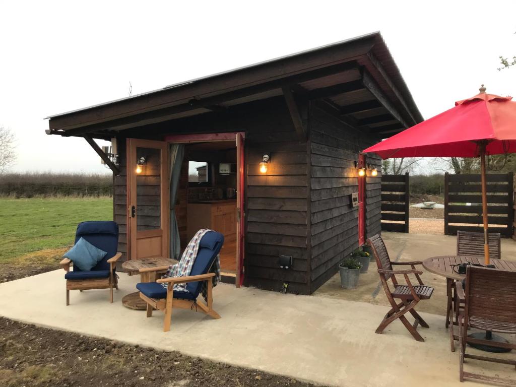a cabin with chairs and tables and a red umbrella at The Little Stable in Corby