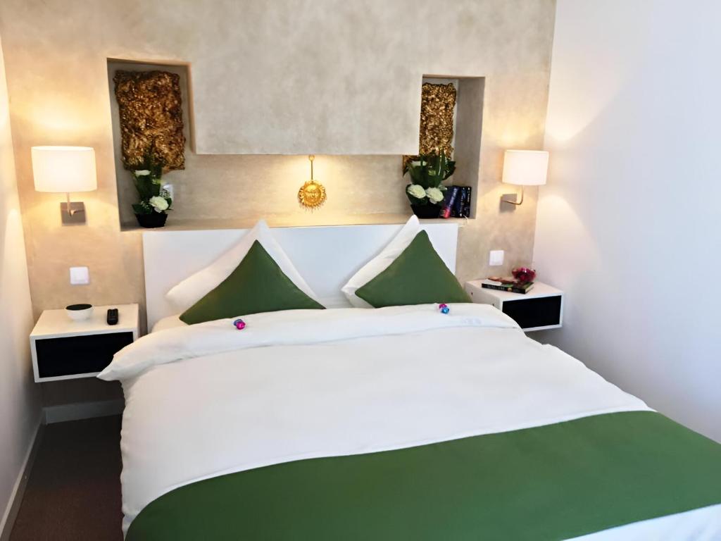 a bedroom with a large white bed with green accents at Csiki Hotel in Miercurea-Ciuc