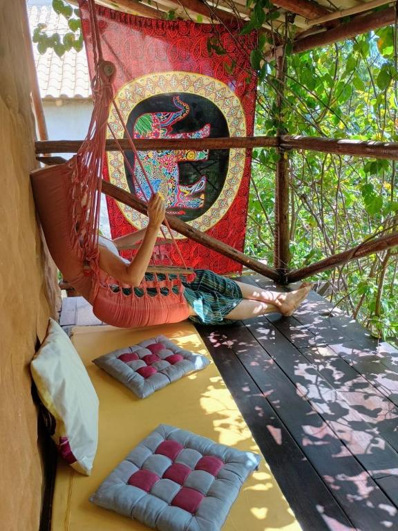 a person laying in a hammock on a porch at Chalé Aconchego in Santo Antônio do Leite