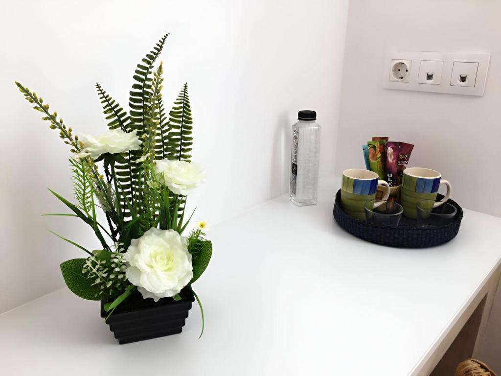 a white counter with a vase of flowers and cups at Csiki Hotel in Miercurea-Ciuc