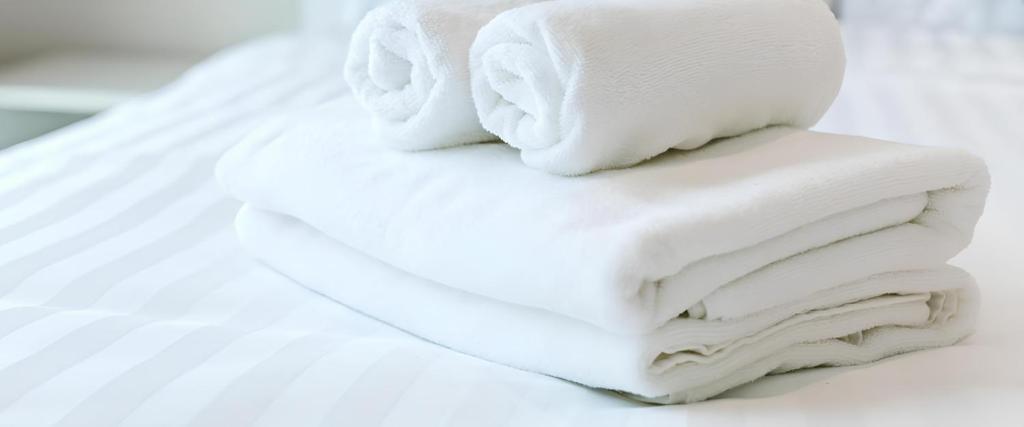 a stack of white towels sitting on top of a bed at Csiki Hotel in Miercurea-Ciuc