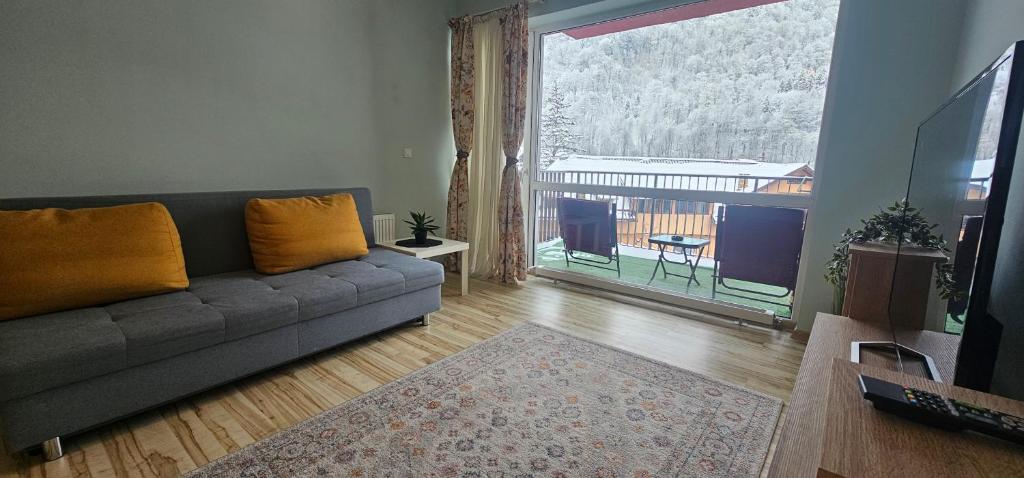 a living room with a couch and a large window at Sinaia Mountain View Residence Belleview in Sinaia