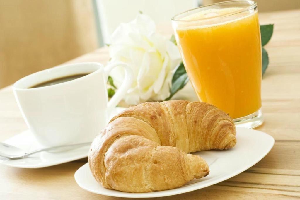 a plate with a croissant and a cup of coffee and orange juice at Csiki Hotel in Miercurea-Ciuc