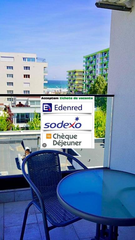 a glass table and a chair in front of a sign at Mamaia-Nord Boutique Apartments in Mamaia Sat/Năvodari