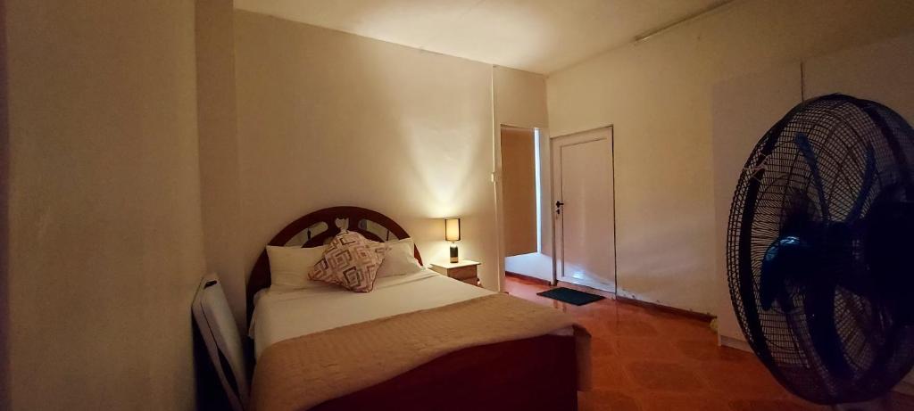 a small bedroom with a bed and a fan at Tamarin Beach House in Tamarin