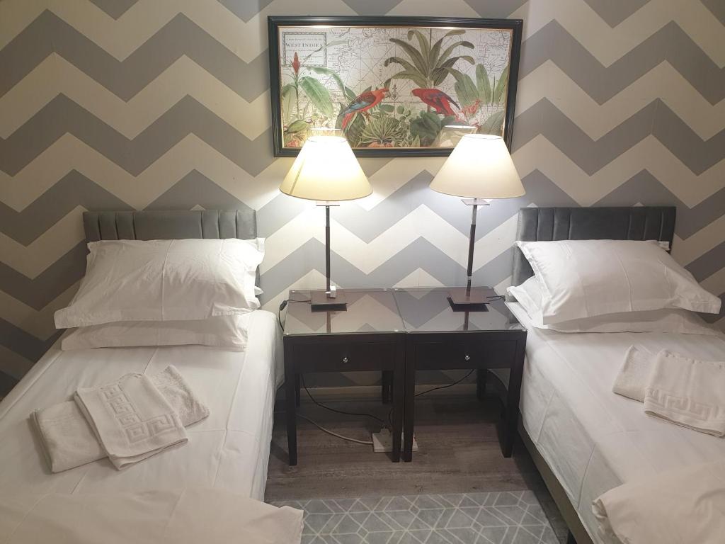 Zimmer mit 2 Betten und einem Schreibtisch mit 2 Lampen in der Unterkunft Spacious, Stylish Two-Bedroom Maisonette, Modern Amenities, Elegant Interiors in Buckinghamshire