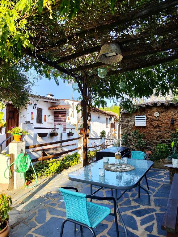 a patio with a table and chairs under a tree at Las Casas de la Tía Sabina in Cortelazor