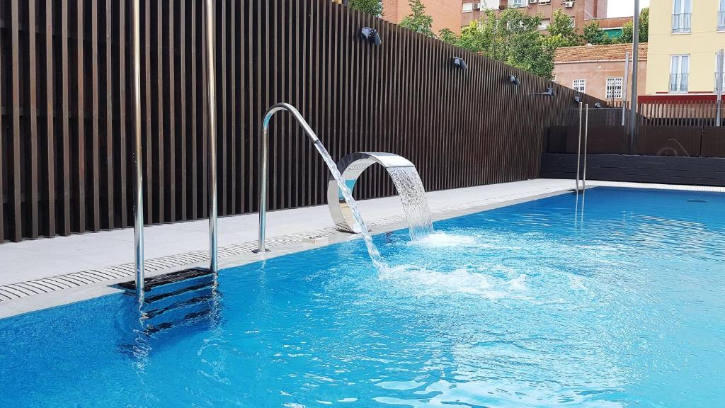 una piscina con una fuente de agua. en Sercotel Alcalá 611, en Madrid