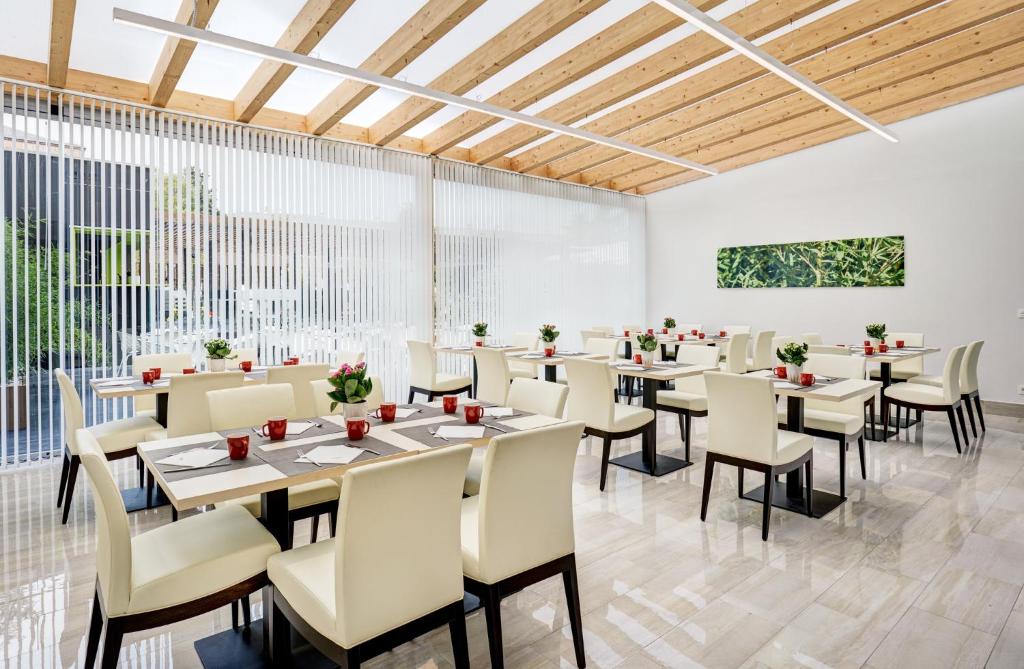 un comedor con mesas, sillas y ventanas en Sercotel Alcalá 611, en Madrid