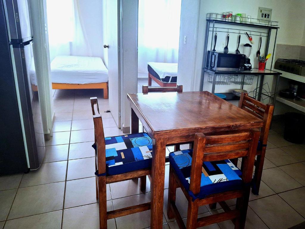 eine Küche mit einem Holztisch und Stühlen sowie eine Küche mit einem Bett in der Unterkunft Departamento En Acapulco Diamante con Alberca, Camastros y Hermosos Jardines in Acapulco