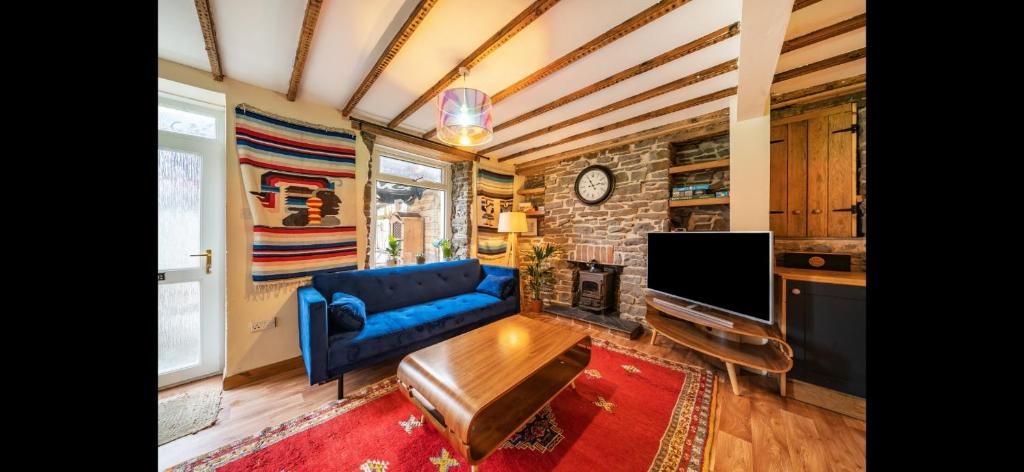 ein Wohnzimmer mit einem blauen Sofa und einem Fernseher in der Unterkunft Quirky Mountain Cottage in Pontardawe
