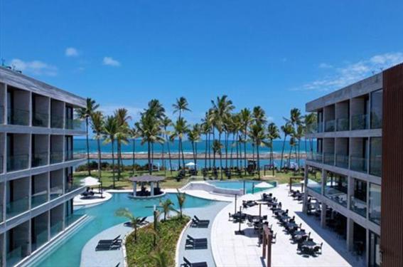 a resort with a pool and palm trees and the ocean at PORTO ALTO RESORT - GAV - Praia do Muro Alto in Ipojuca