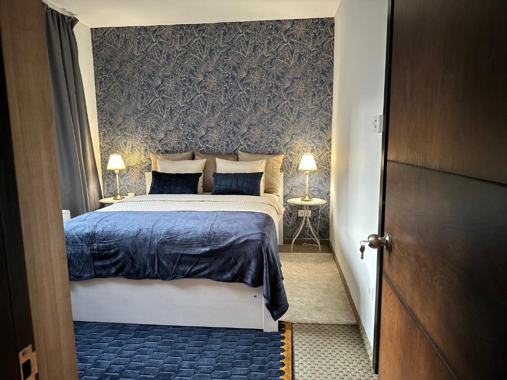 a bedroom with a bed with blue sheets and a wall at Wellness Spa Suite by the Opera in Budapest