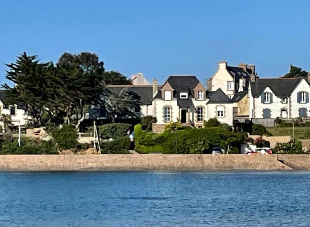 une grande maison assise à côté d'une nappe d'eau dans l'établissement Résidence V50-perros Guirec - Villa vue mer sur le port de Ploumanac'h MAE-4134, à Perros-Guirec