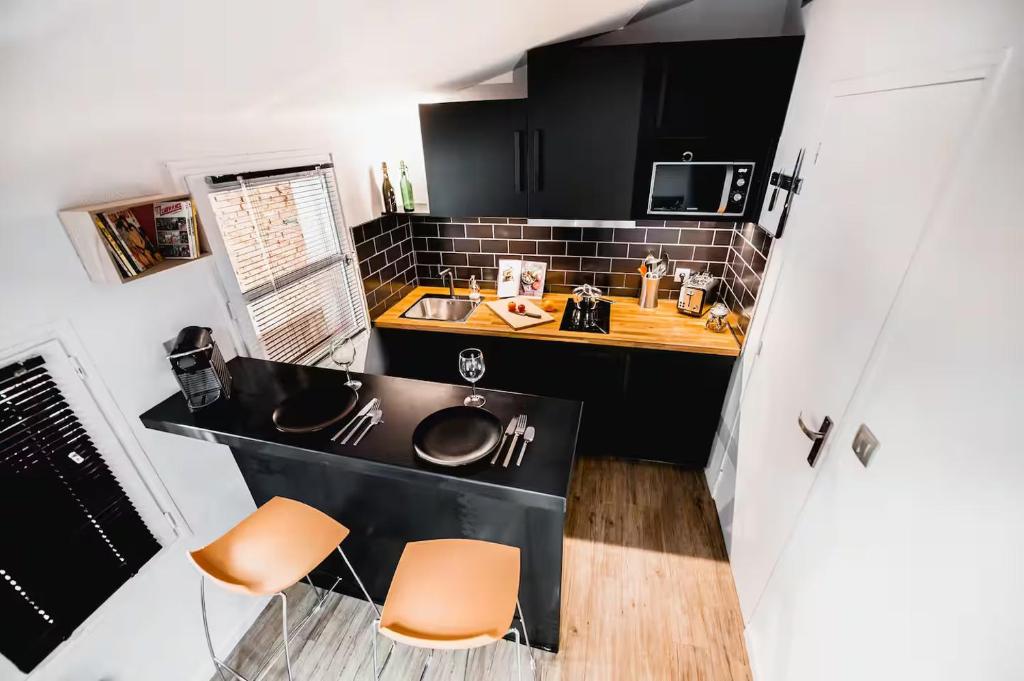 Il comprend une petite cuisine avec un évier et des chaises orange. dans l'établissement Charmant studio climatisé au cœur de Toulouse - Quartier des Carmes, à Toulouse