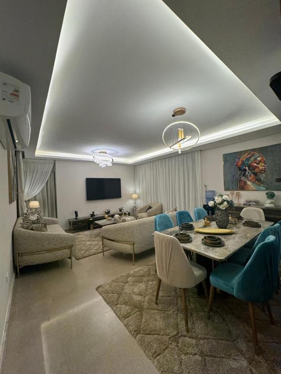 a living room with a table and blue chairs at Zed towers El sheikh ZAYED zed park 3 in Sheikh Zayed