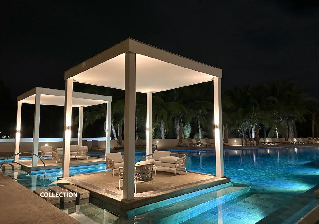 a pool with chairs and a pavilion at night at Residence by Mio Nuevo Vallarta 103-C in Nuevo Vallarta