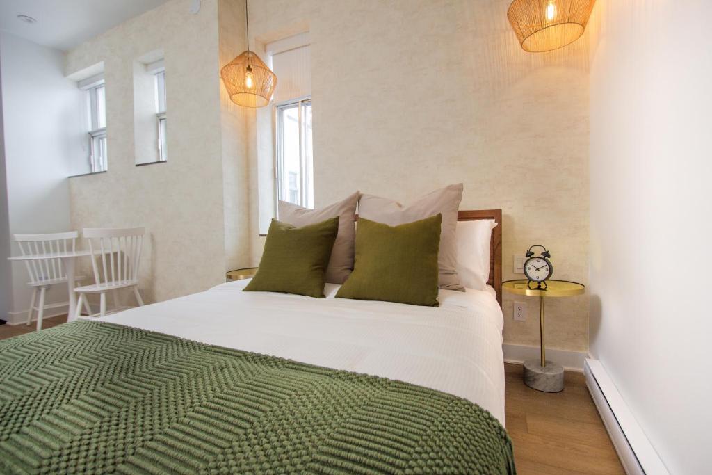 a bedroom with a large white bed with green pillows at Studio #18 - Self Check-In - Plateau - St-Denis in Montreal