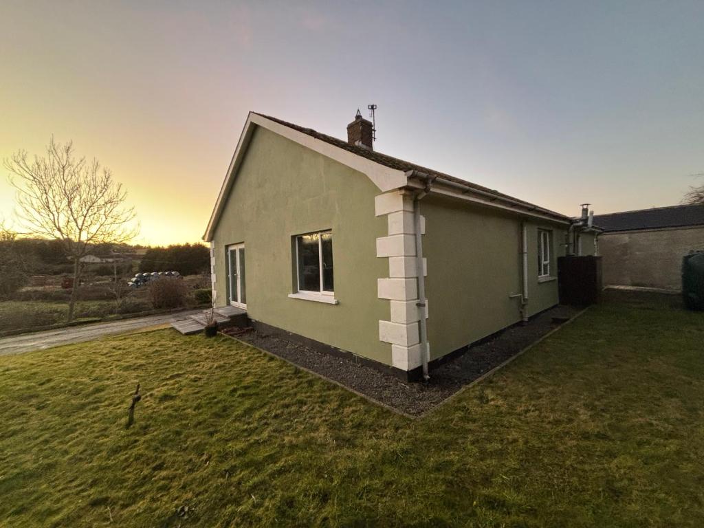 a green house with a grass yard at Christinas Cottage Downpatrick in Raholp