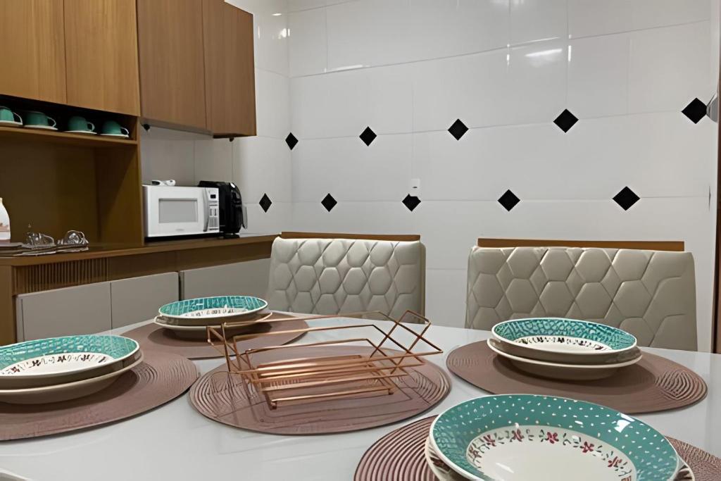 a kitchen with a table with plates and chairs at Apartamento aconchegante próximo à Faculdade in Araxá