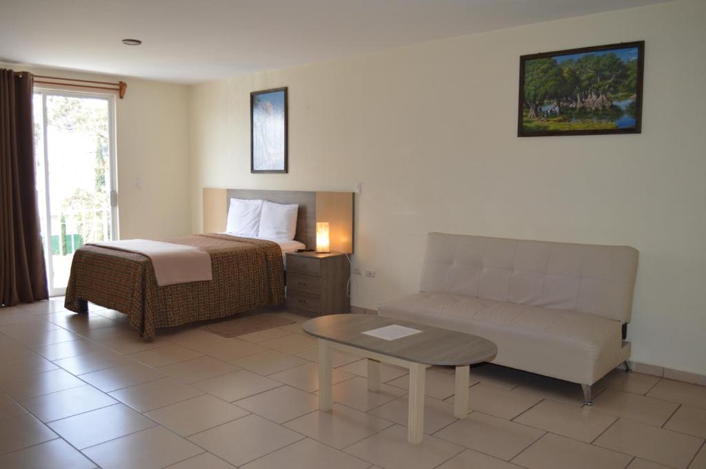 een slaapkamer met een bed, een bank en een tafel bij Hotel Ciprés Puebla in La Concepción