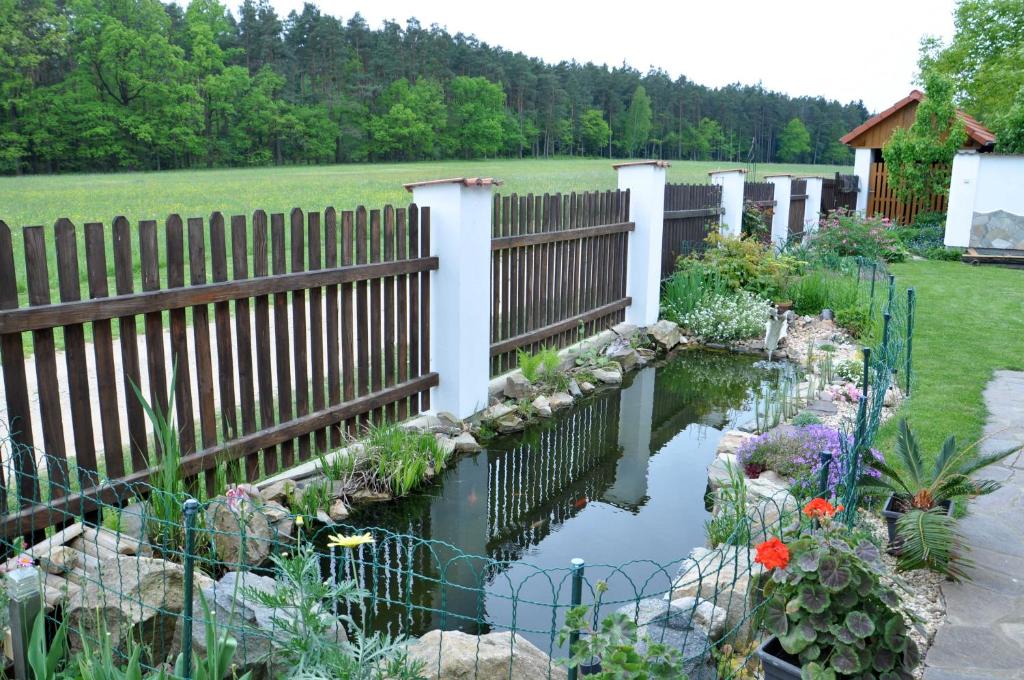 a garden with a fence and a pond at Apartments Odměny U Třeboně in Třeboň