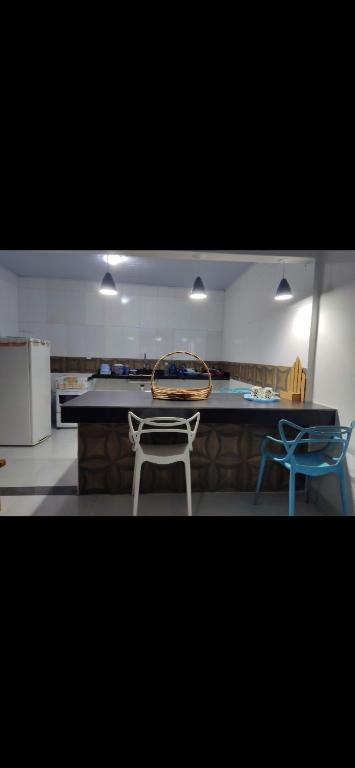 a kitchen with a table and two blue chairs at Residencial Franco Casa 02 in Primavera do Leste