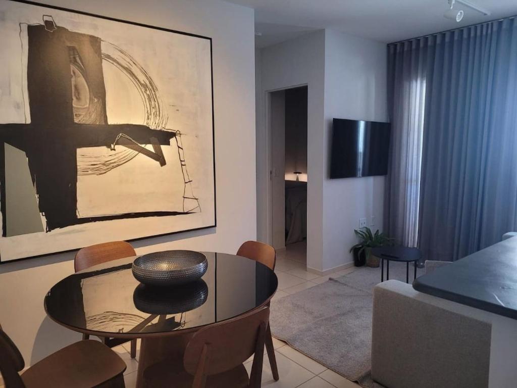 een woonkamer met een tafel en een foto aan de muur bij Apartamento Urbano 02 dormitórios in Marília
