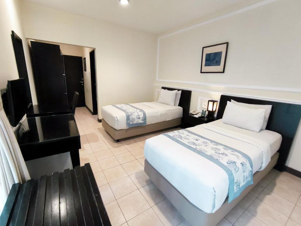 Postel nebo postele na pokoji v ubytování Puteri Gunung Hotel