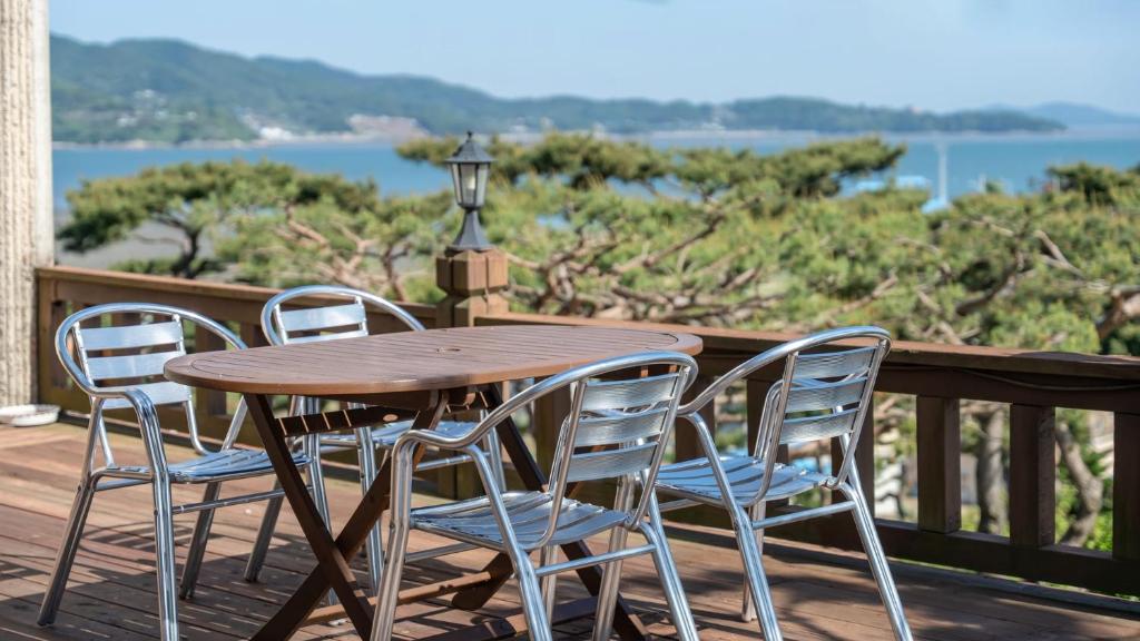 Una mesa de madera y cuatro sillas en una terraza. en Seokmodo supsokbadapunggyeong pension, en Incheon