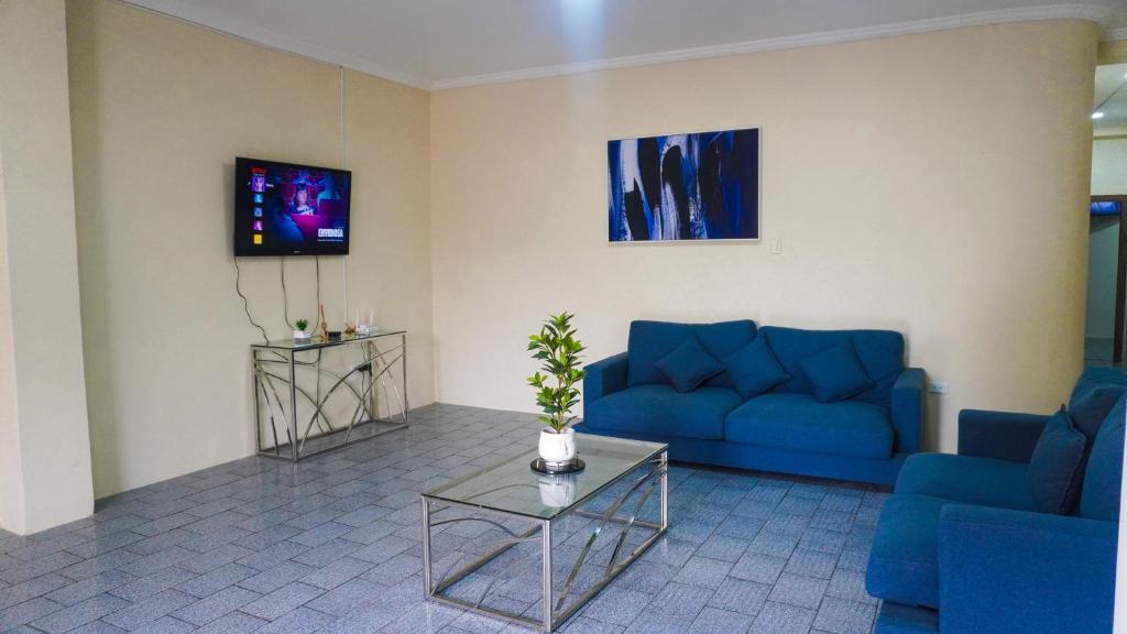 a living room with blue couches and a tv at Departamento completo, facso in Cuatro Hermanas