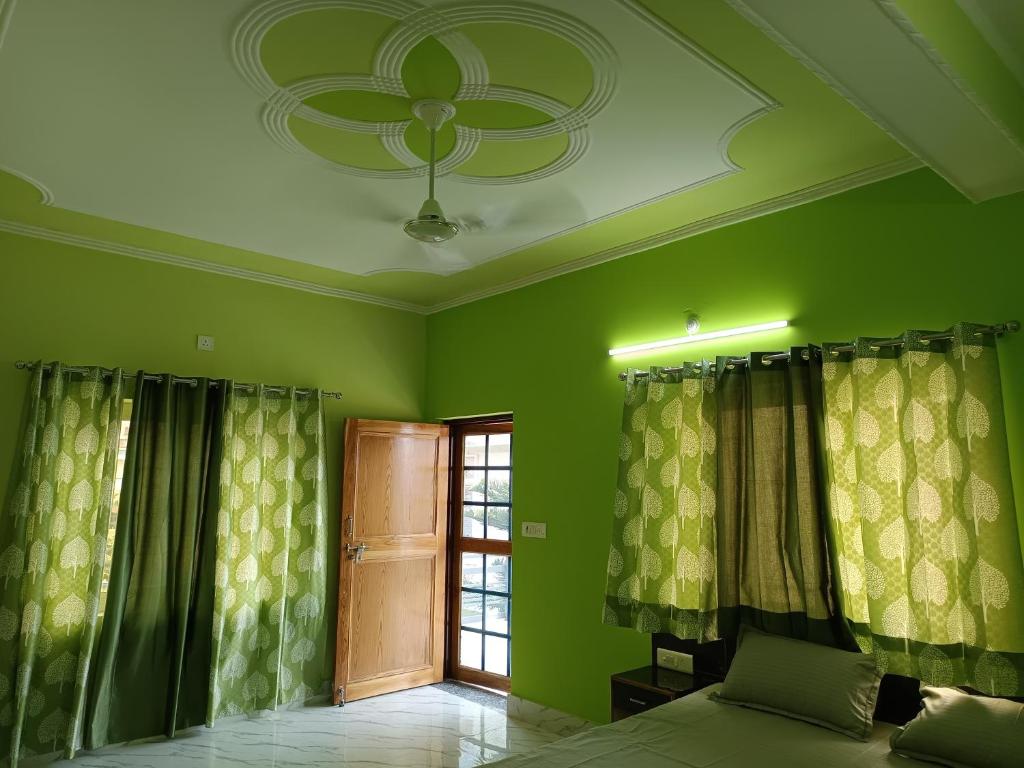 a green room with a ceiling fan and a window at Welcome Home Stay & Hotel Tapovan Rishikesh in Rishīkesh