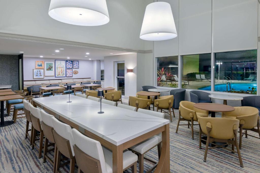 a dining room with tables and chairs and a pool at Homewood Suites by Hilton Bonita Springs, FL in Bonita Springs
