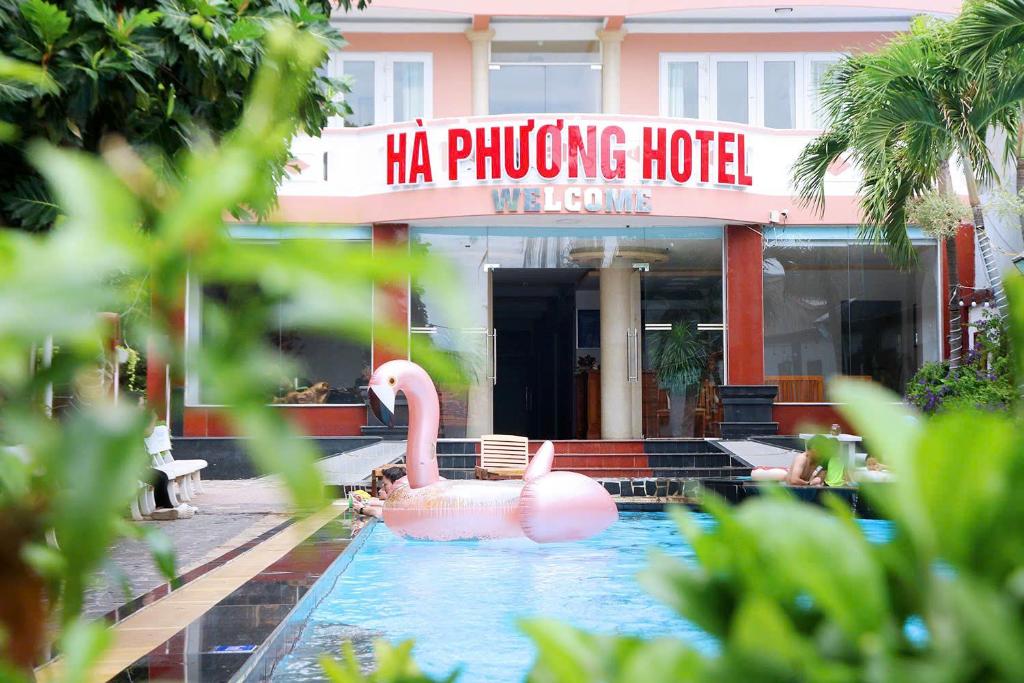 a pink swan in the water in front of a hotel at Ha Phuong Mui Ne Hotel in Mui Ne