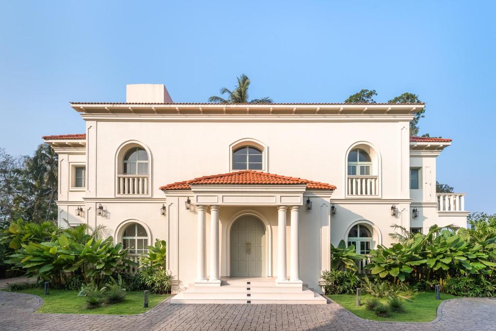una gran casa blanca con árboles delante de ella en LohonoStays Villa Lanai, en Arpora