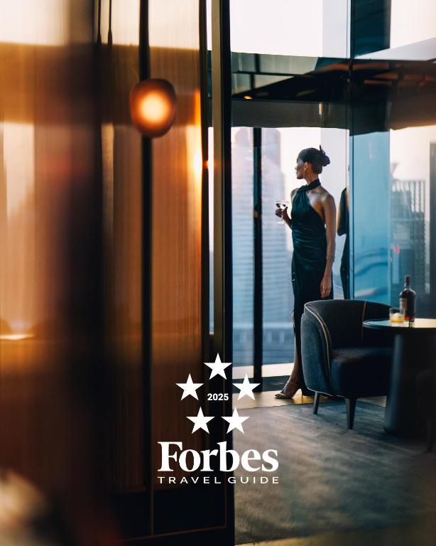 Eine Frau, die aus dem Fenster schaut und ihr Handy ansieht. in der Unterkunft Marina Bay Sands in Singapur