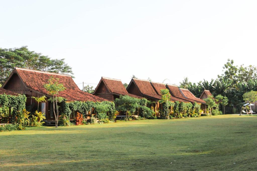 une rangée de maisons aux toits rouges sur un terrain herbeux dans l'établissement Ijen Estate Resort And Villa, à Banyuwangi