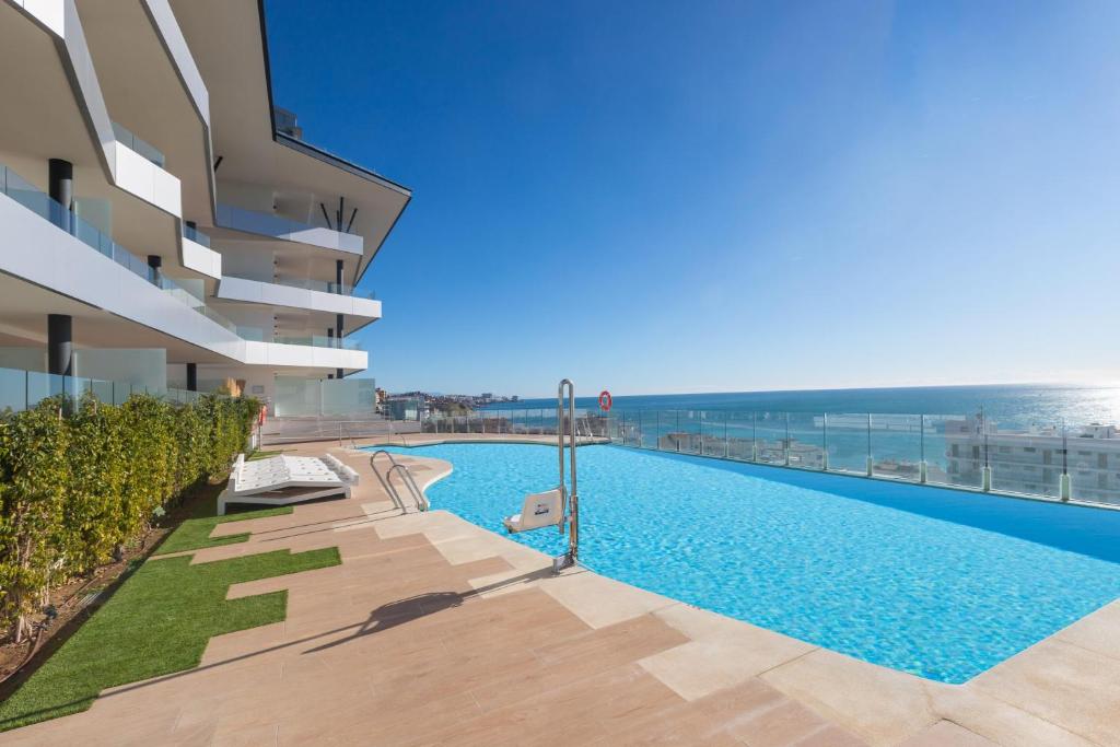 a swimming pool next to a building with the ocean at Begoña Sea View in Fuengirola