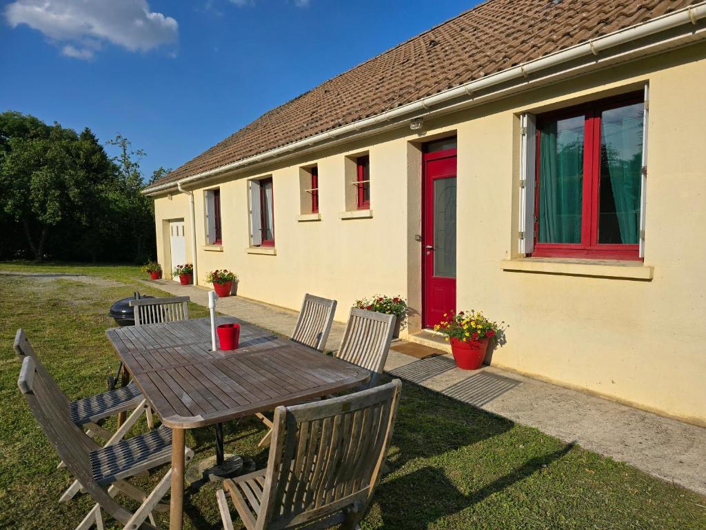 a wooden table and chairs in front of a house at Pause calme au cœur du Perche in Saint-Hilaire-le-Châtel