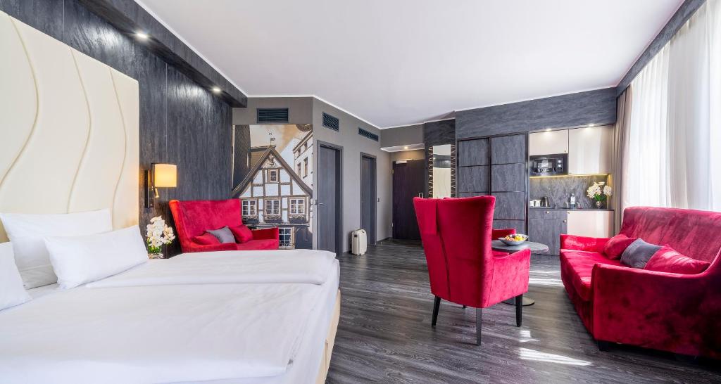 a bedroom with a bed and two red chairs at PLAZA Premium Schwerin Sure Hotel Collection by Best Western in Schwerin