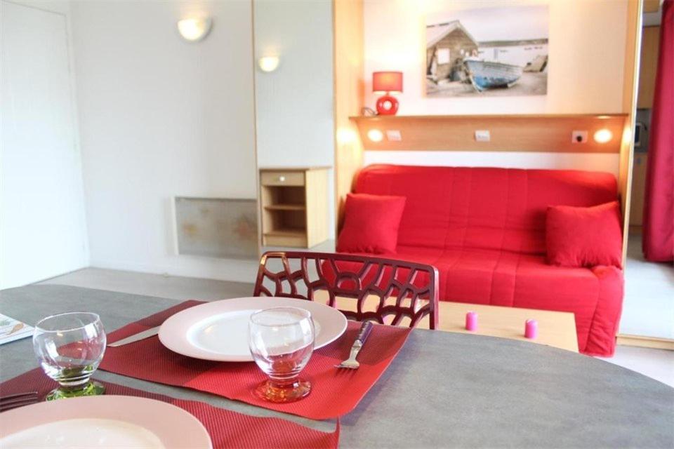 - une table à manger avec un canapé rouge dans le salon dans l'établissement Appt Studio LA ROCHELLE - LR010-212, à La Rochelle