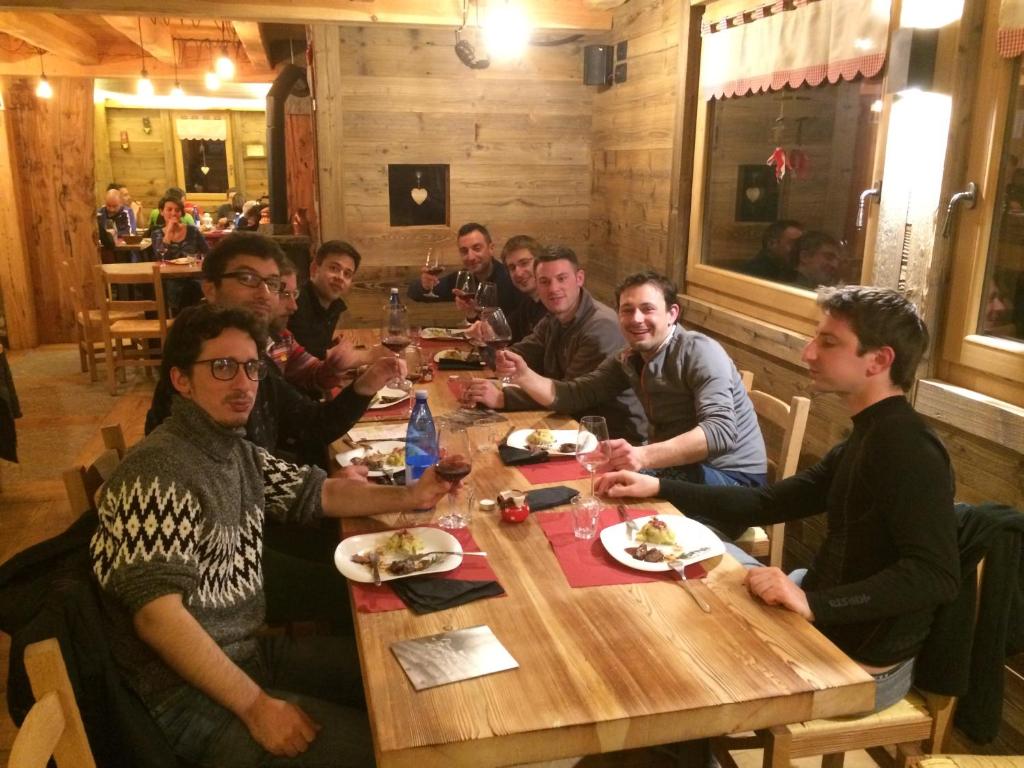 Un gruppo di uomini seduti intorno a un tavolo in un ristorante di Rifugio Luna Nascente a San Martino