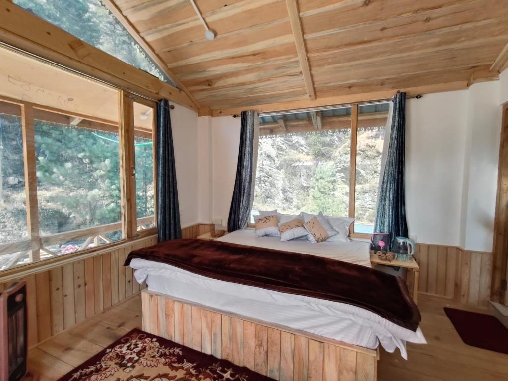 a bedroom with a bed in a room with windows at Shreya cozy hut in Sainj