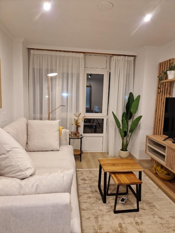 a living room with a white couch and a table at La Flor del Cantábrico in Ribadeo