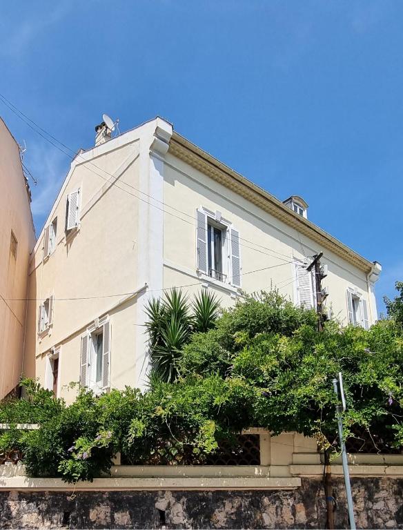 un grand bâtiment blanc avec des buissons devant lui dans l'établissement Villa Magenta, à Cannes