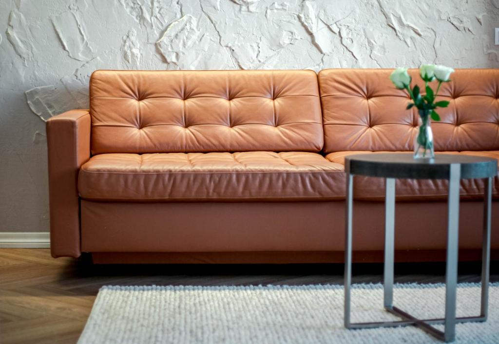 a orange couch with a vase of flowers on a table at Nordic Bliss Apartment 1 in Inari