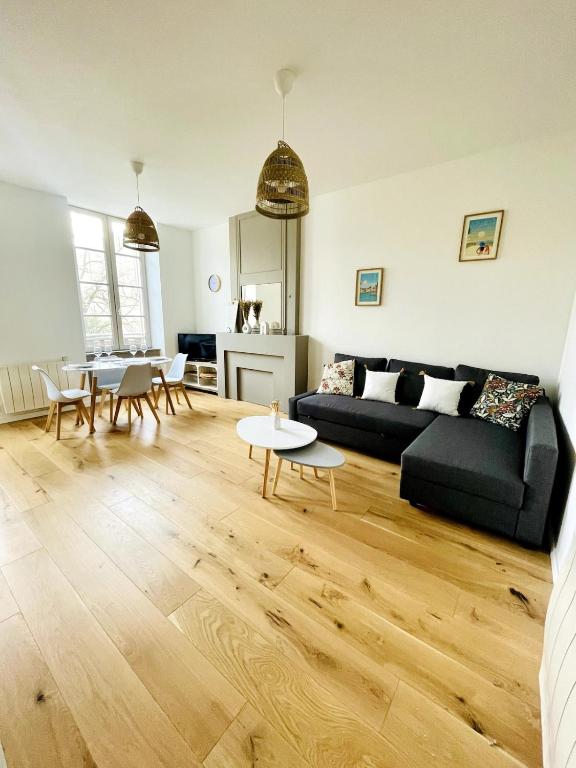 un salon avec un canapé noir et une table dans l'établissement Le Saint-Louis l Coeur de Ville, à La Rochelle