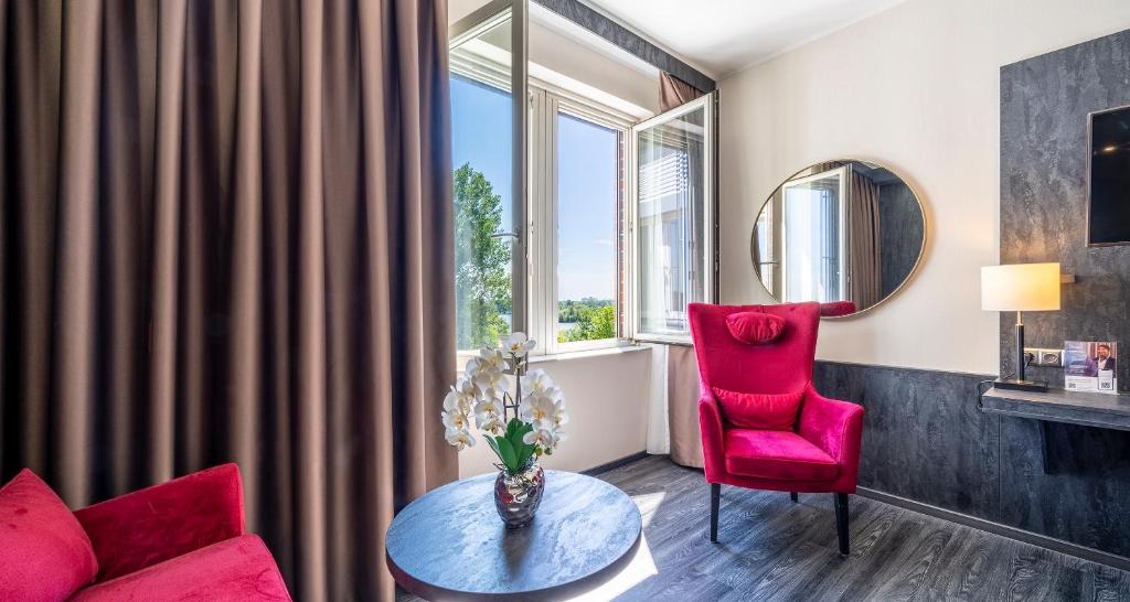 a living room with a red chair and a table at PLAZA Premium Schwerin in Schwerin