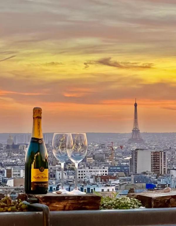 - une bouteille de vin et des verres à vin sur un livre avec la tour de l'eiffel dans l'établissement Terrasse avec vue magique sur tout Paris, à Paris