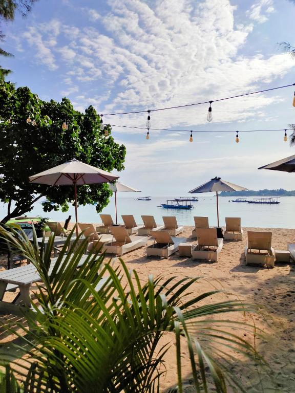 a group of chairs and umbrellas on a beach at Bale Sampan Boutique Bungalows in Gili Trawangan